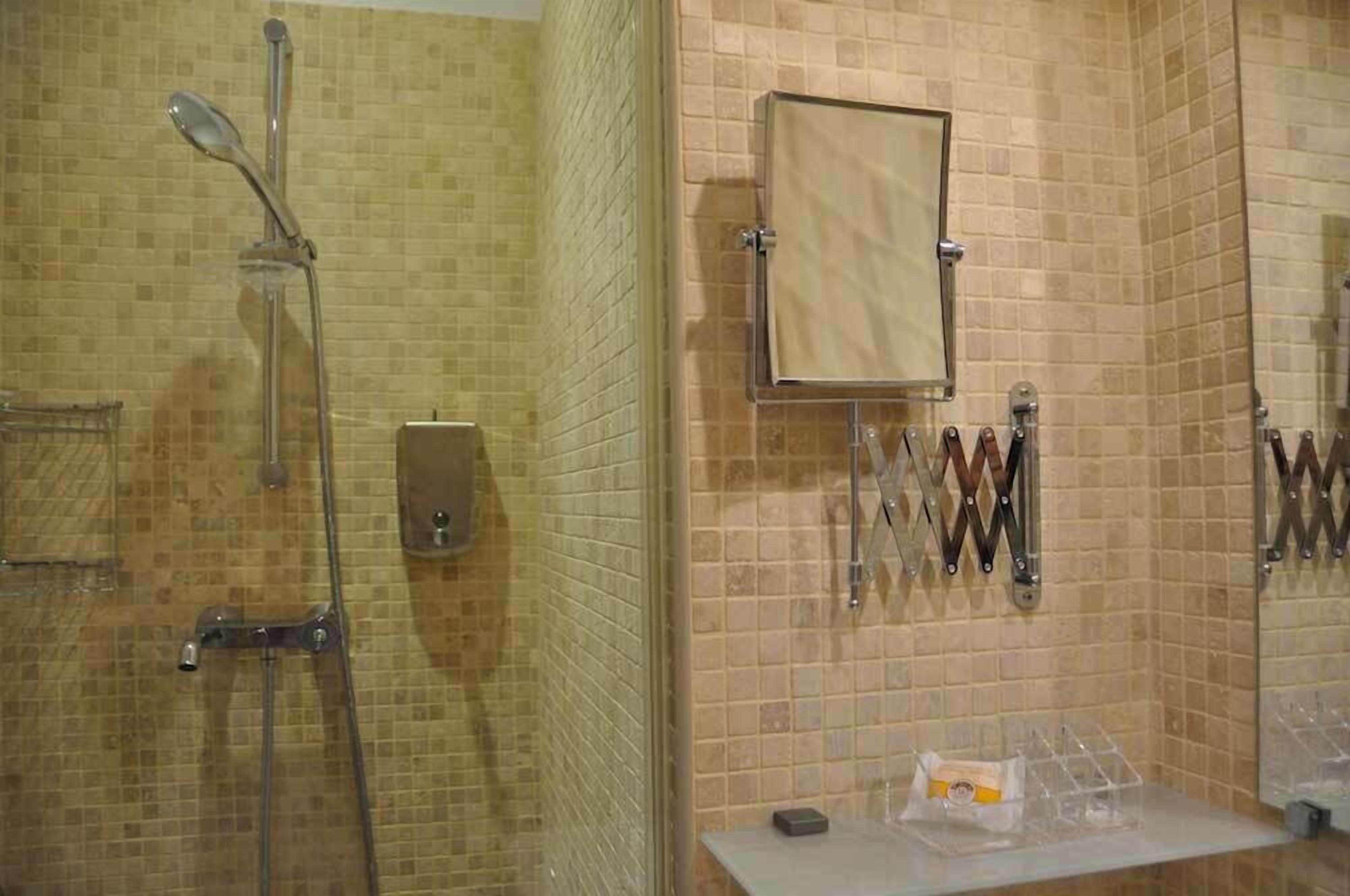 A bathroom with a shower, a towel rack, and a soap dispenser.