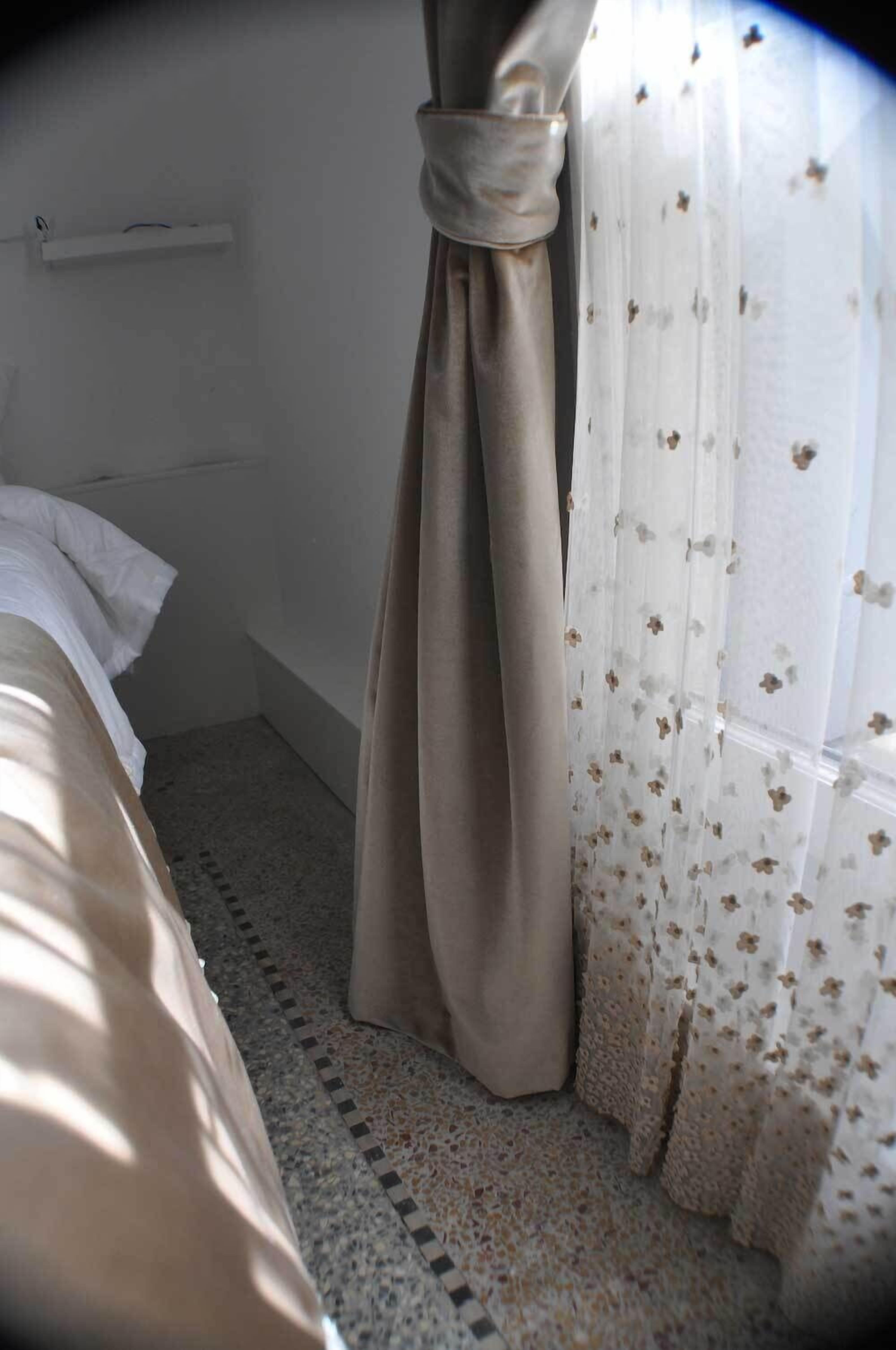 Un dormitorio con cama, cortina y ventana con cortinas florales.