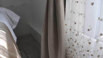 Un dormitorio con cama, cortina y ventana con cortinas florales.