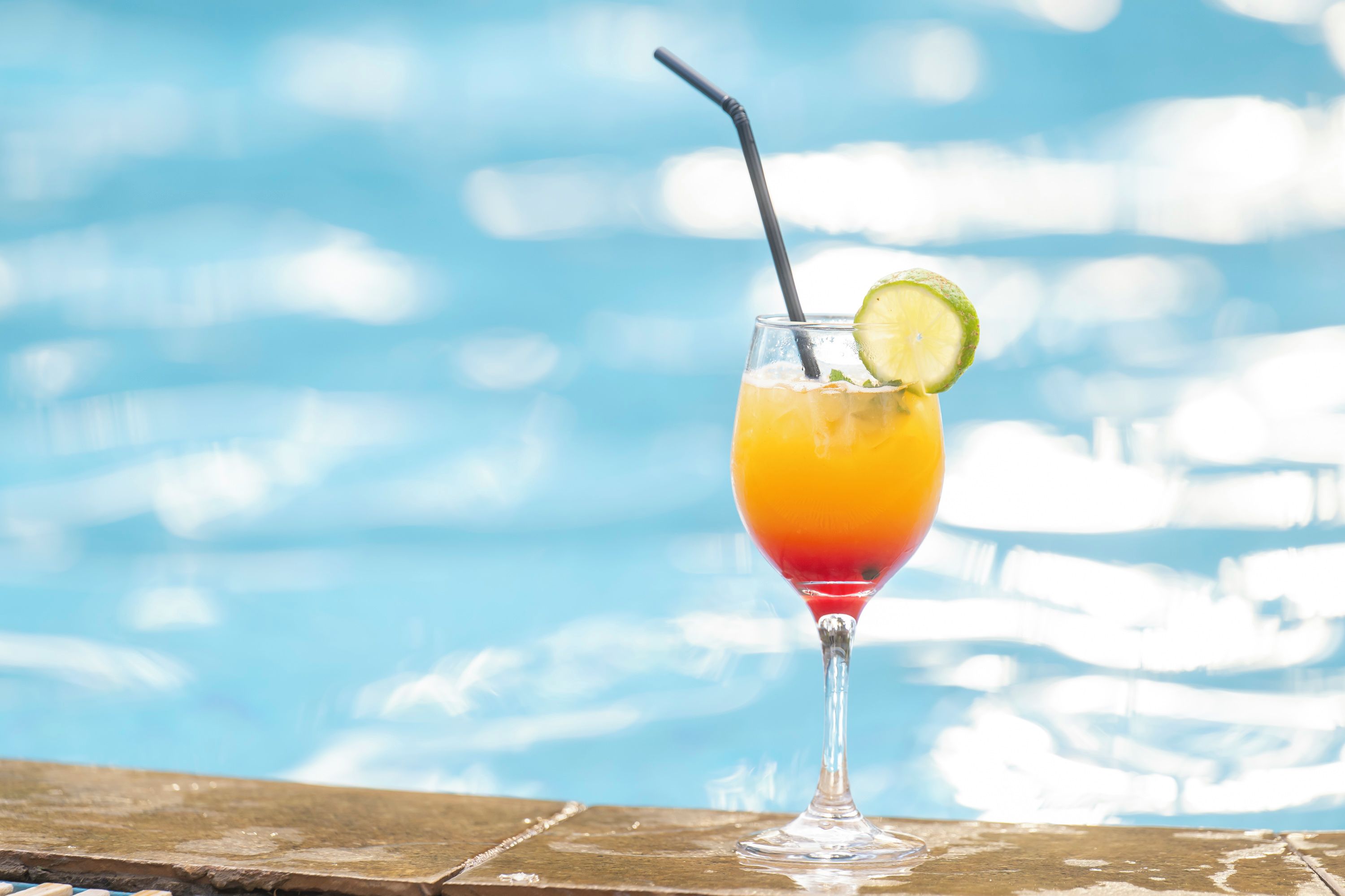 Een cocktail met een limoen schuimend aan een zwembad.