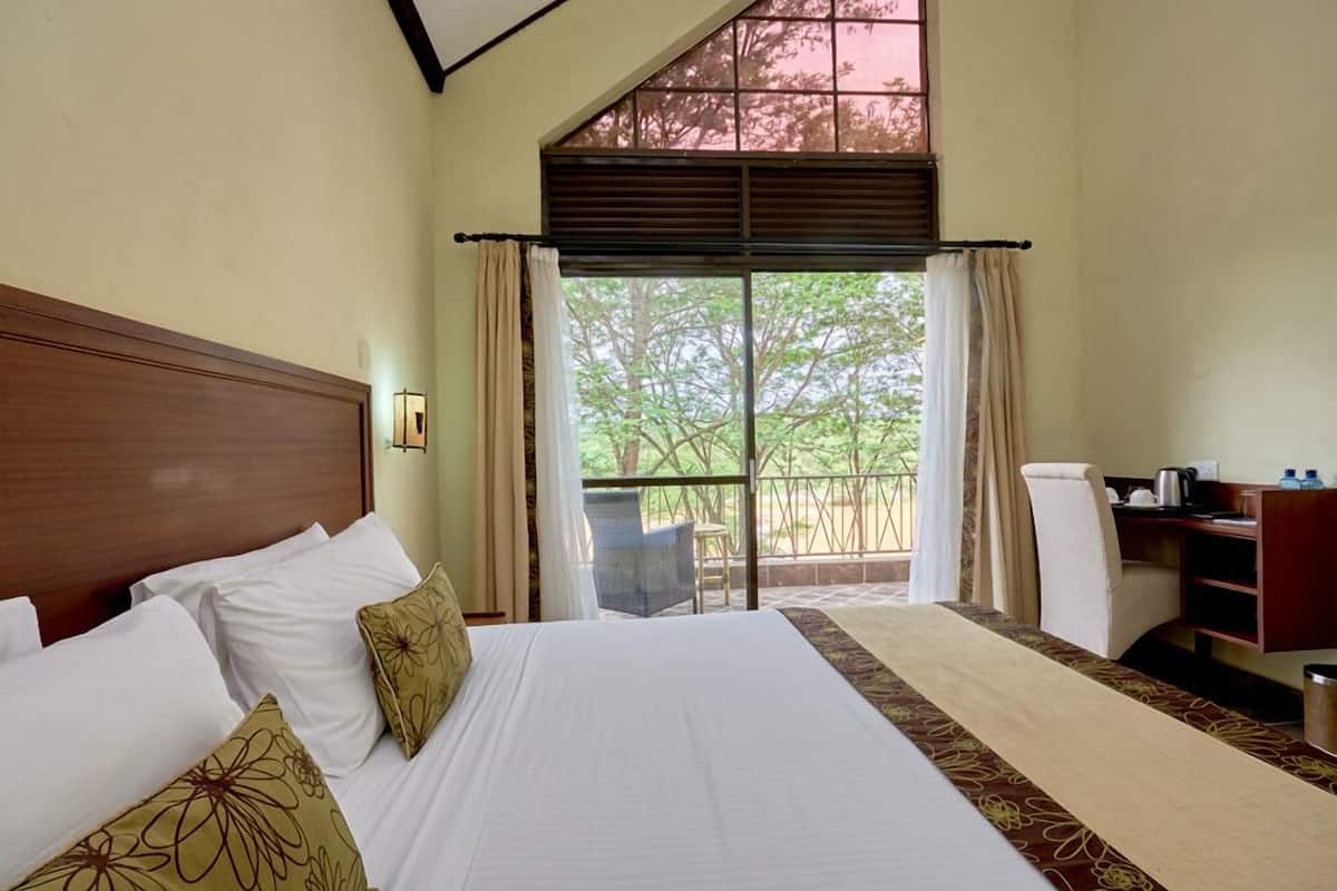 A hotel room with a large bed, a desk, and a view of the outdoors.