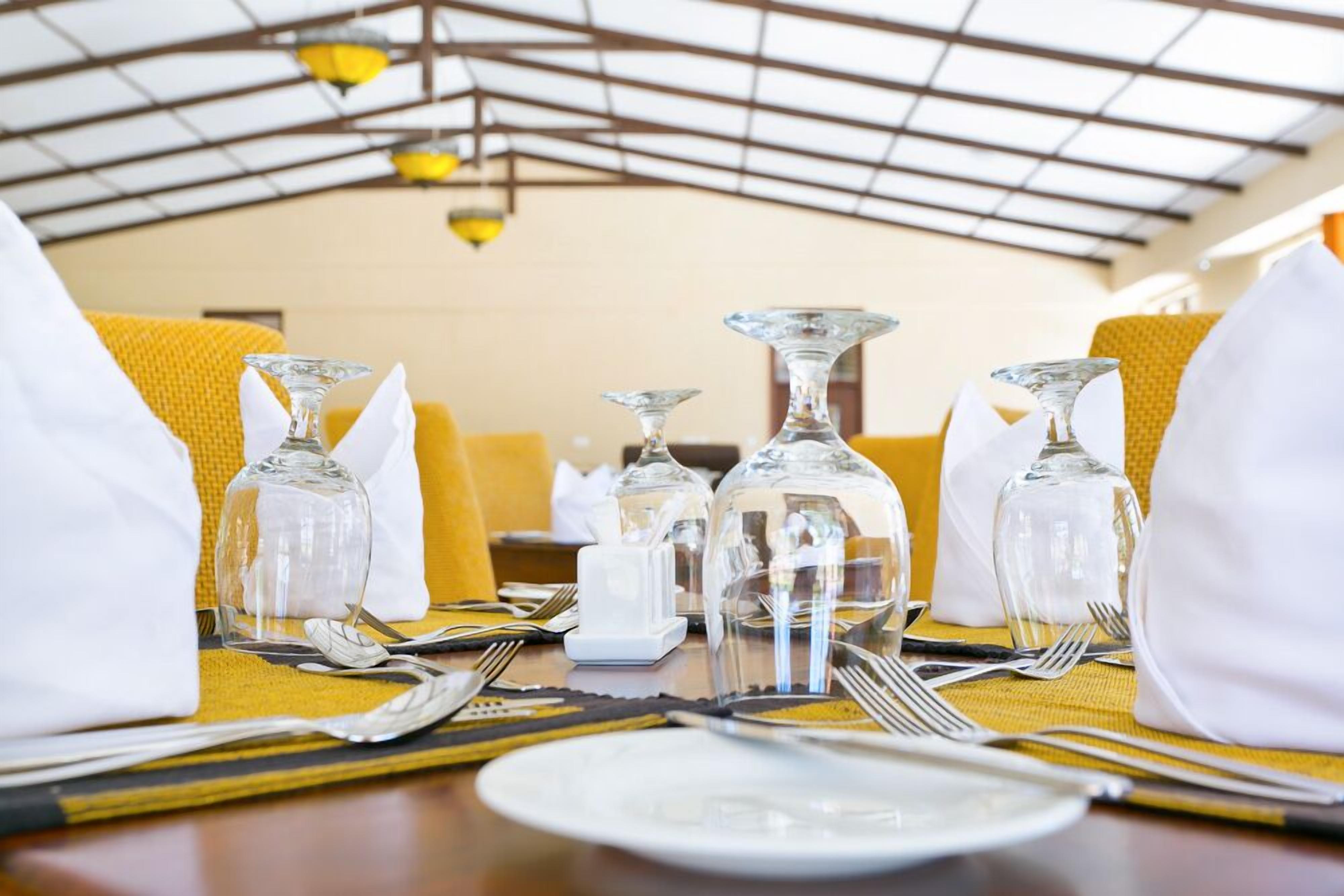 Una mesa de comedor dispuesta con servilletas blancas, cristalería transparente y cubiertos.