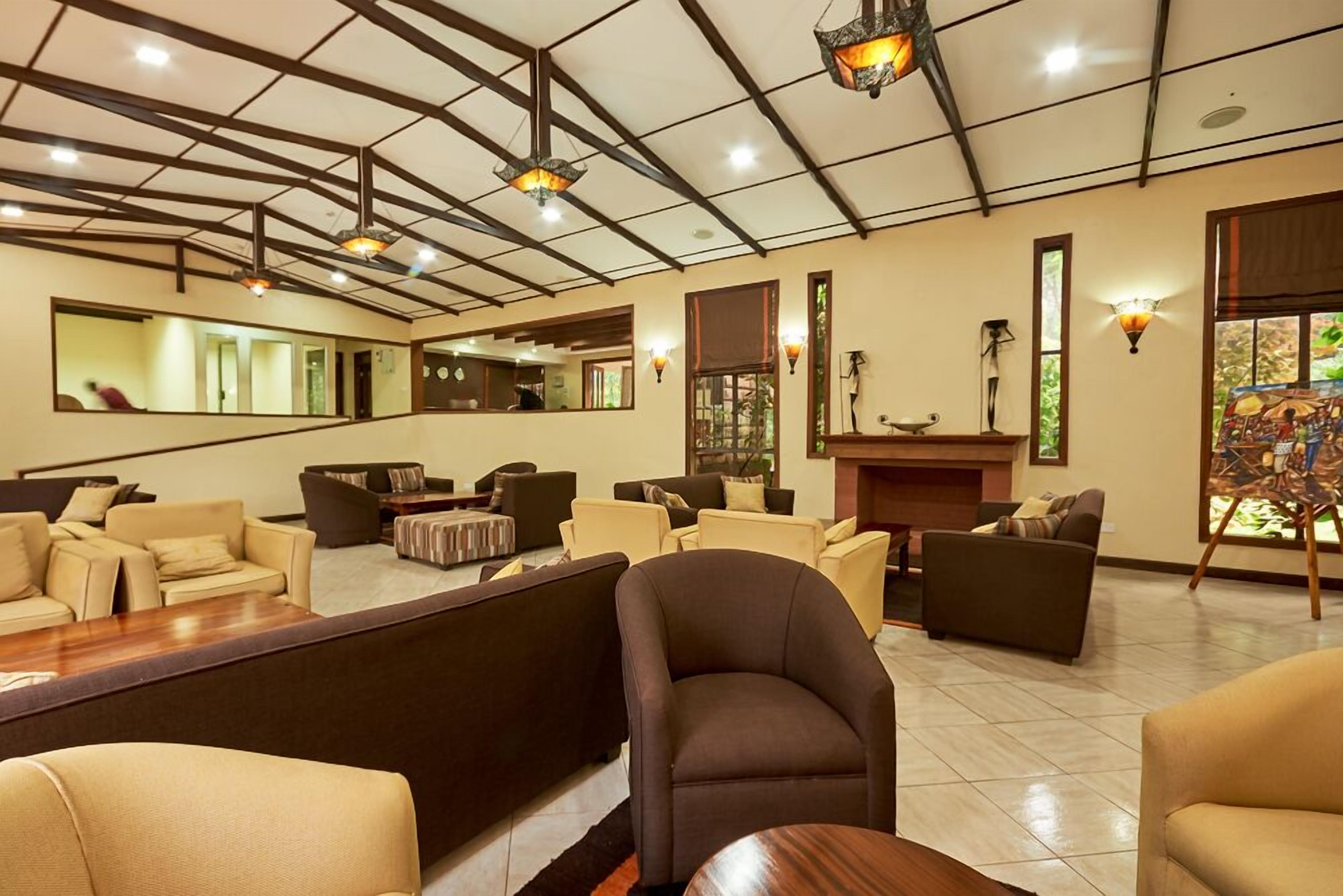 A spacious lobby with multiple seating areas, a reception desk, and a large mirror reflecting the interior.