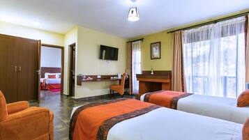 A hotel room with two beds, a desk, a chair, a TV, and a bathroom.