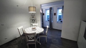 A dining area with a round table, four chairs, a candelabra, and a hanging light fixture.