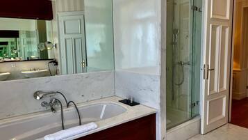 Une salle de bain moderne avec un lavabo en marbre, une baignoire, une douche à l’italienne et un grand miroir.