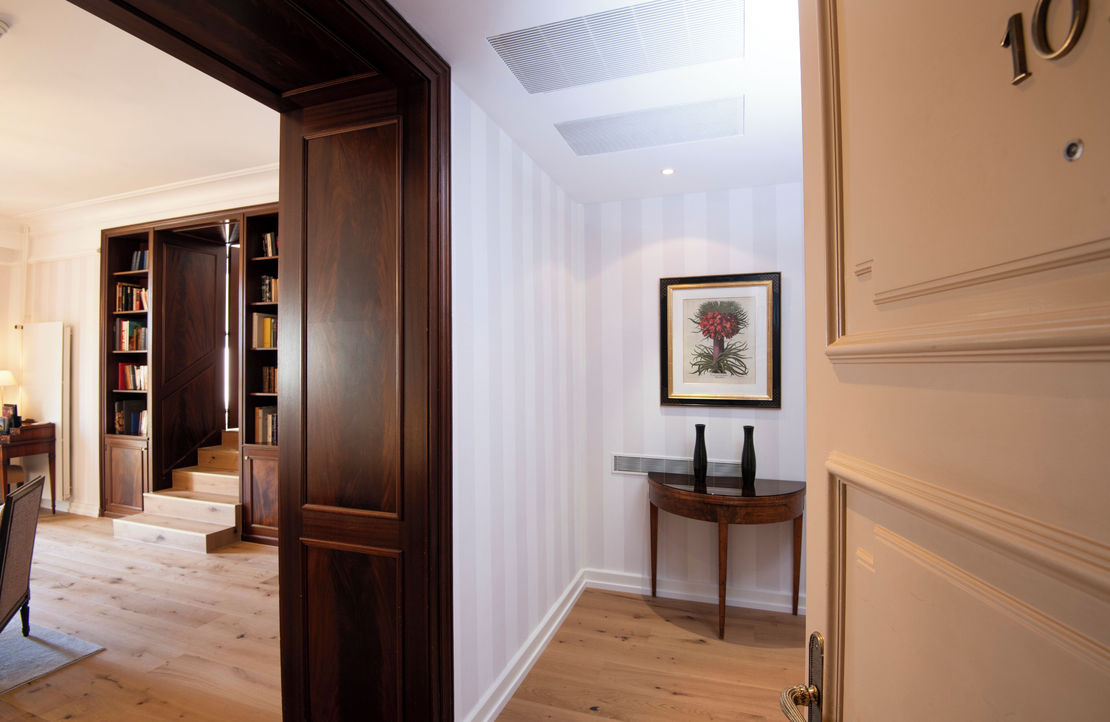 A hallway with a wooden door labeled '10', a staircase, and a bookshelf.