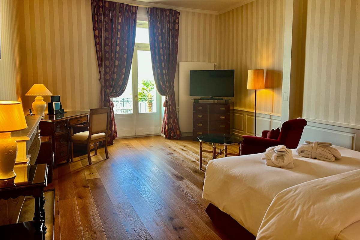 Ein Hotelzimmer mit Bett, Schreibtisch mit Lampe, Fernseher und Sessel.