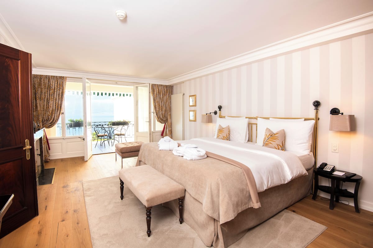 Ein Schlafzimmer mit einem großen Bett, einer Bank, einem Nachttisch und Blick ins Freie.