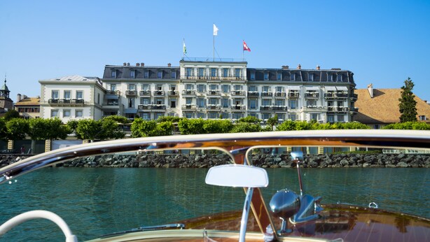 Un hôtel situé au bord de l’eau, doté de nombreux balcons, d’un drapeau et offrant une vue sur le plan d’eau.