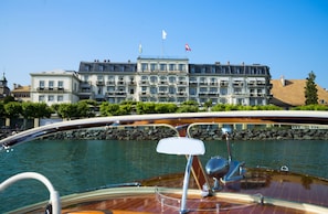 Un hotel frente al agua con varios balcones, una bandera y vistas al agua.
