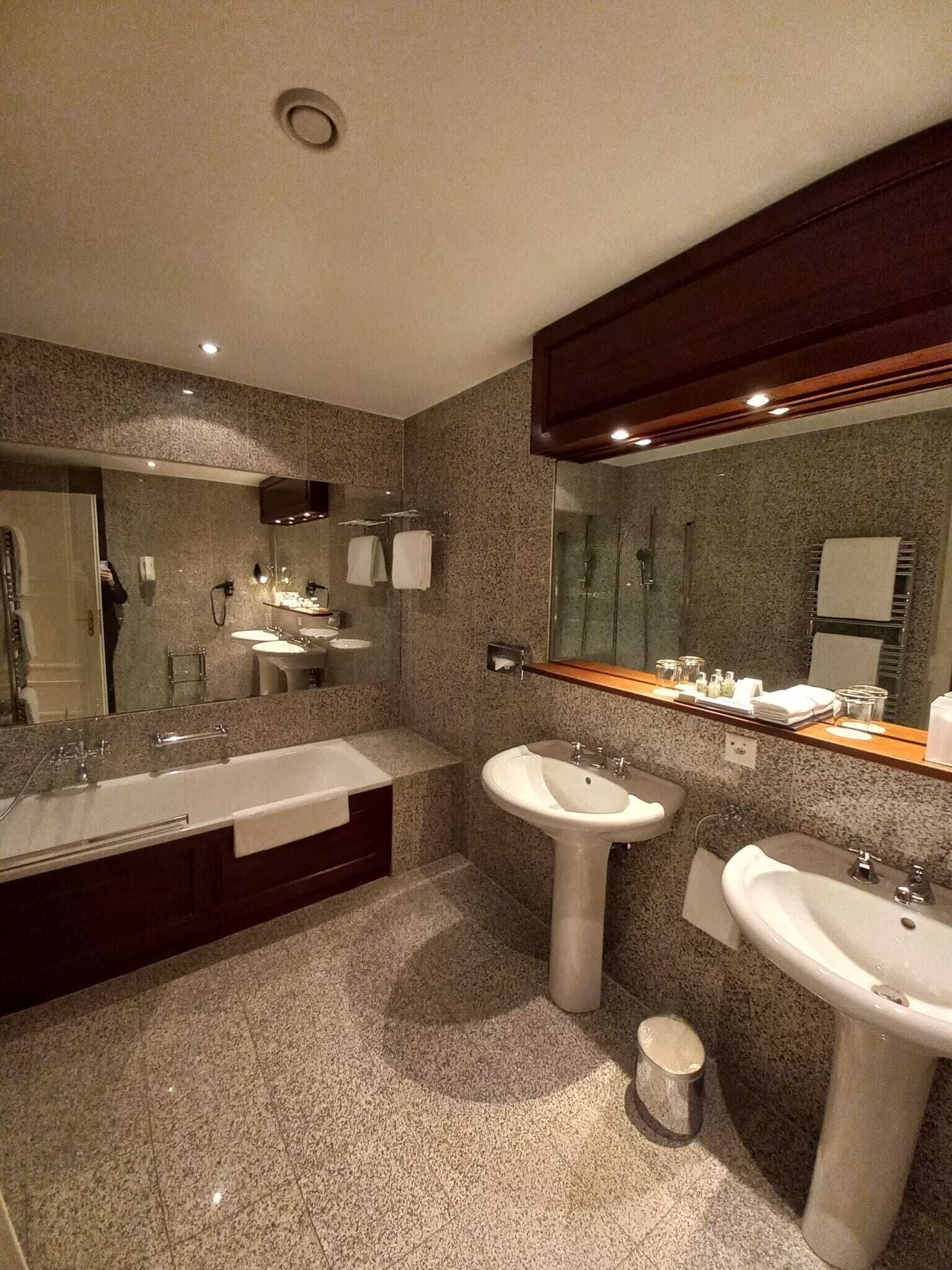 A modern bathroom with two sinks, a bathtub, and a shower.