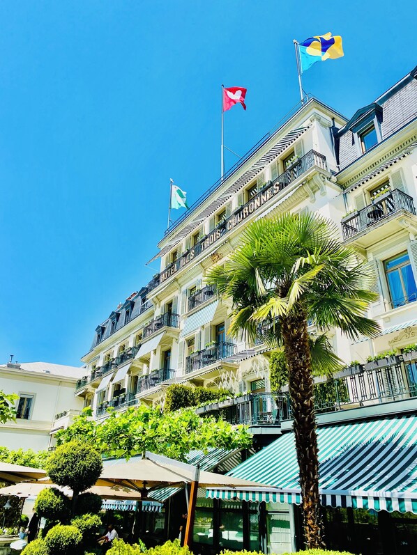 Un hotel de varios pisos con balcones, una palmera y banderas.