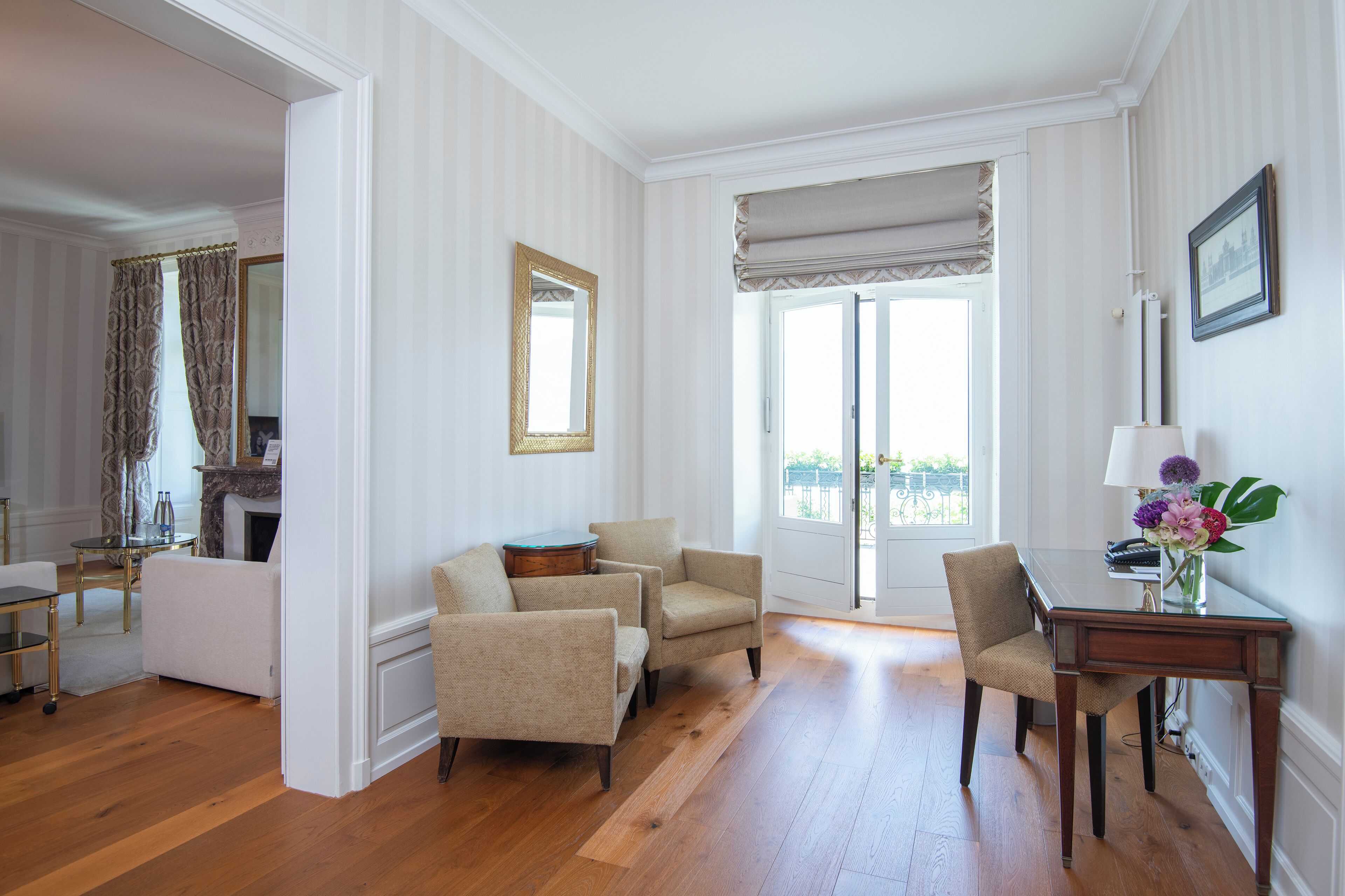 A spacious room with a wooden floor, a dining table with chairs, a sofa, and a fireplace.