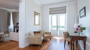 A spacious room with a wooden floor, a dining table with chairs, a sofa, and a fireplace.