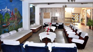A hotel lobby with a mural, seating areas, and a staircase. - Hotel Vinayakam (Udaipur)