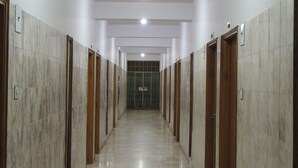 A long, narrow hallway with marble walls and doors, leading to a green-tiled room at the end. - Hotel Vinayakam (Udaipur)