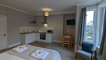 Une chambre d’hôtel avec une kitchenette, un lit avec des serviettes, une chaise et une fenêtre donnant sur un paysage agréable.