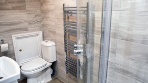 Une salle de bain comprenant des toilettes, un lavabo et une douche à parois en verre.