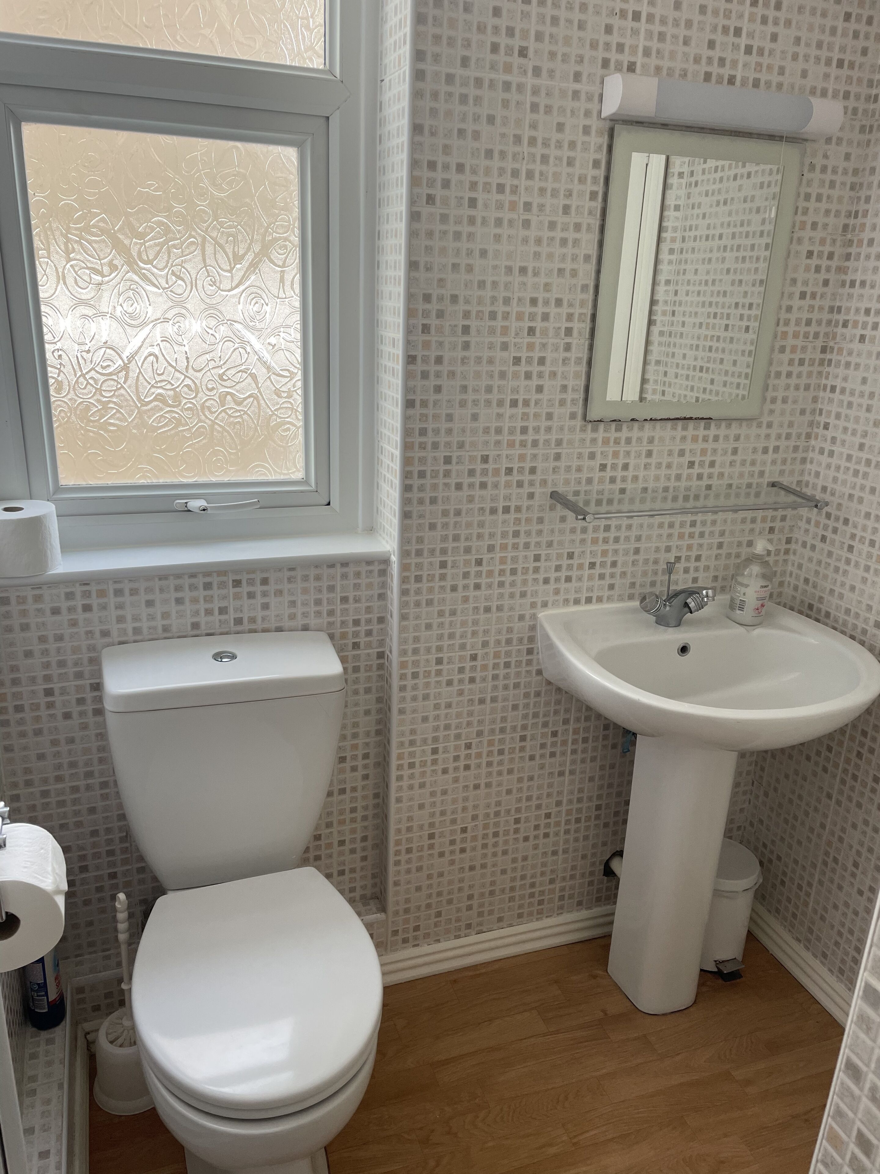Une salle de bain avec des toilettes, un lavabo et une fenêtre.