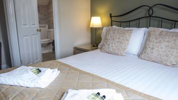 A hotel room with a bed, a nightstand, a lamp, and a bathroom visible through an open door.