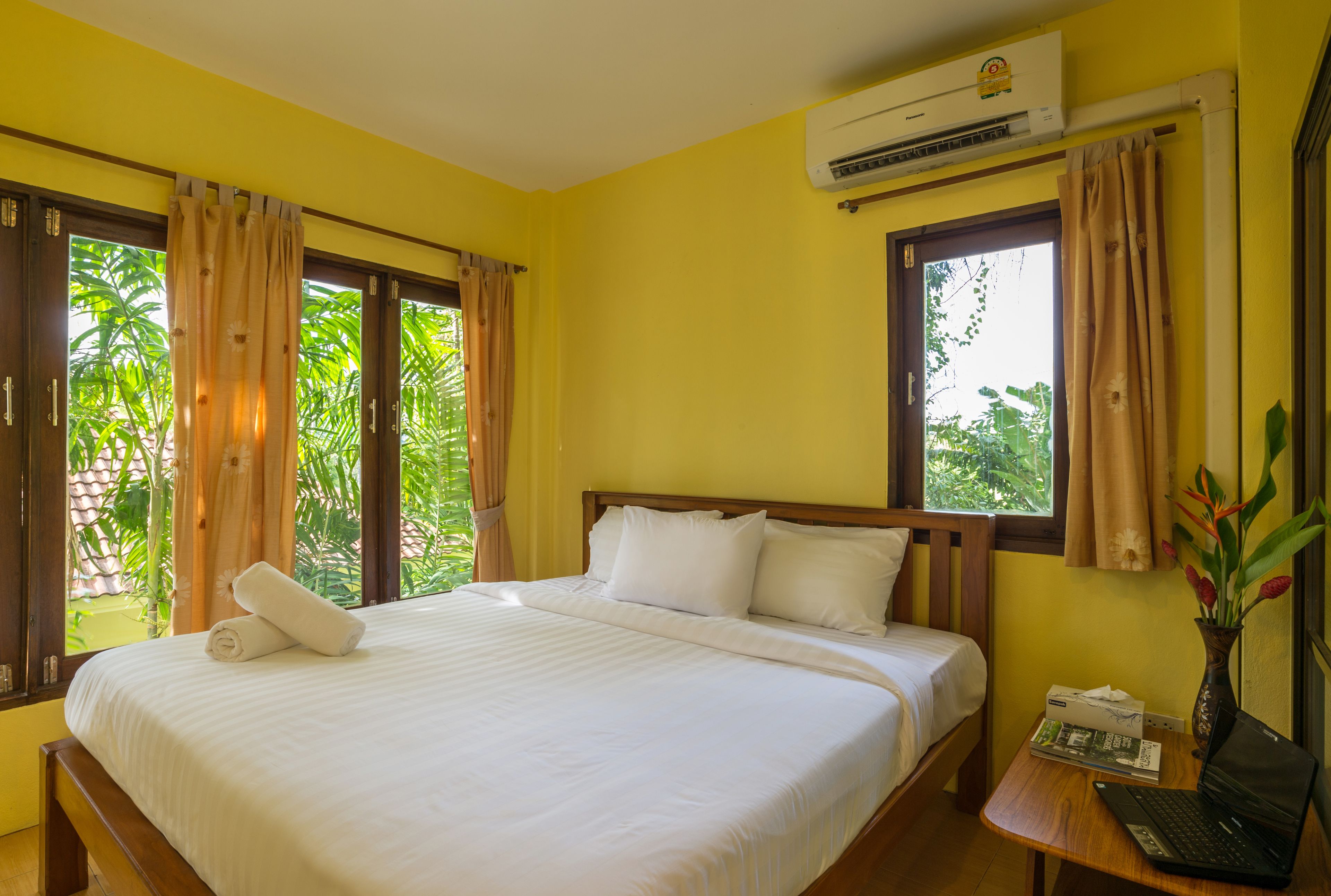 Une chambre d’hôtel avec un lit, un bureau avec un ordinateur portable et une fenêtre avec des rideaux.