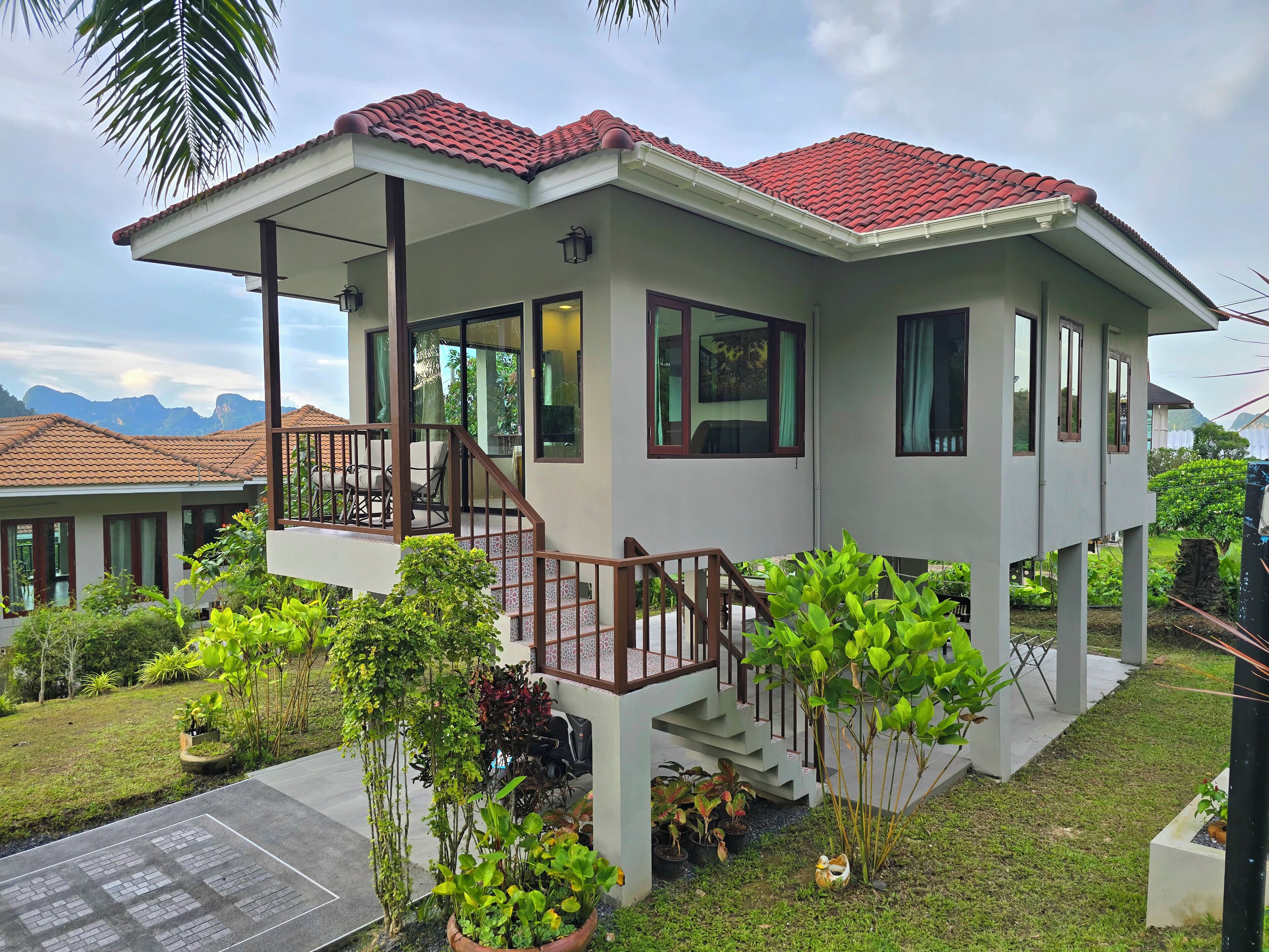 A two-story house with a balcony, a covered porch, and a view of mountains.