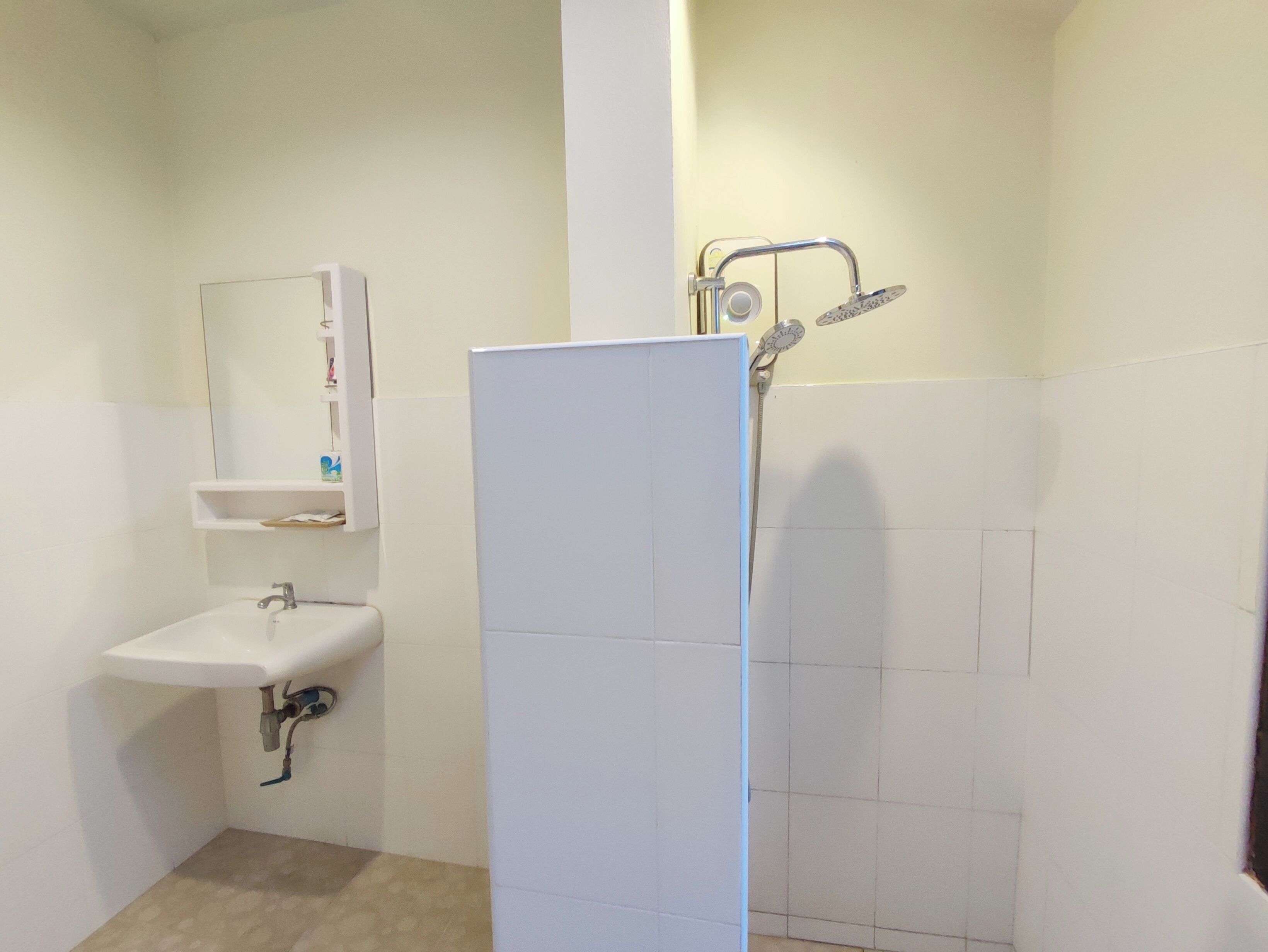 Un baño con lavamanos, espejo y ducha blancos.