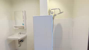 Un baño con lavamanos, espejo y ducha blancos.