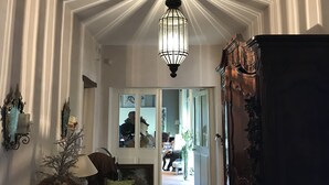 Una habitación con techo estampado, una lámpara colgante y vista a otra habitación.