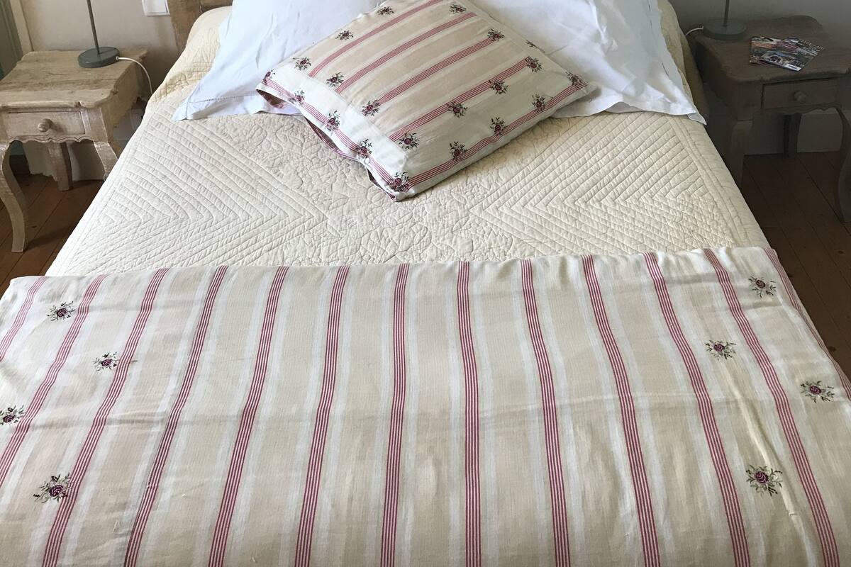Una cama con cabecera de madera, dos lámparas de noche y una colcha a rayas.