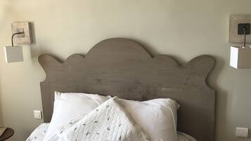Una cama con edredón blanco acolchado y almohadas, un cabecero de madera y mesitas de noche con lámparas.