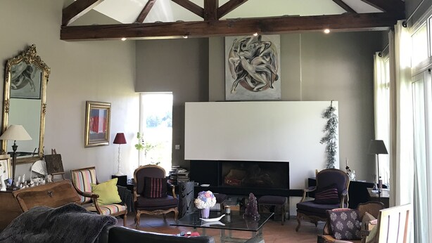 Amplia sala de estar con vigas de madera a la vista, chimenea y asientos cómodos.