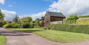 A modern house with a gravel driveway, surrounded by well-maintained lawns and hedges.