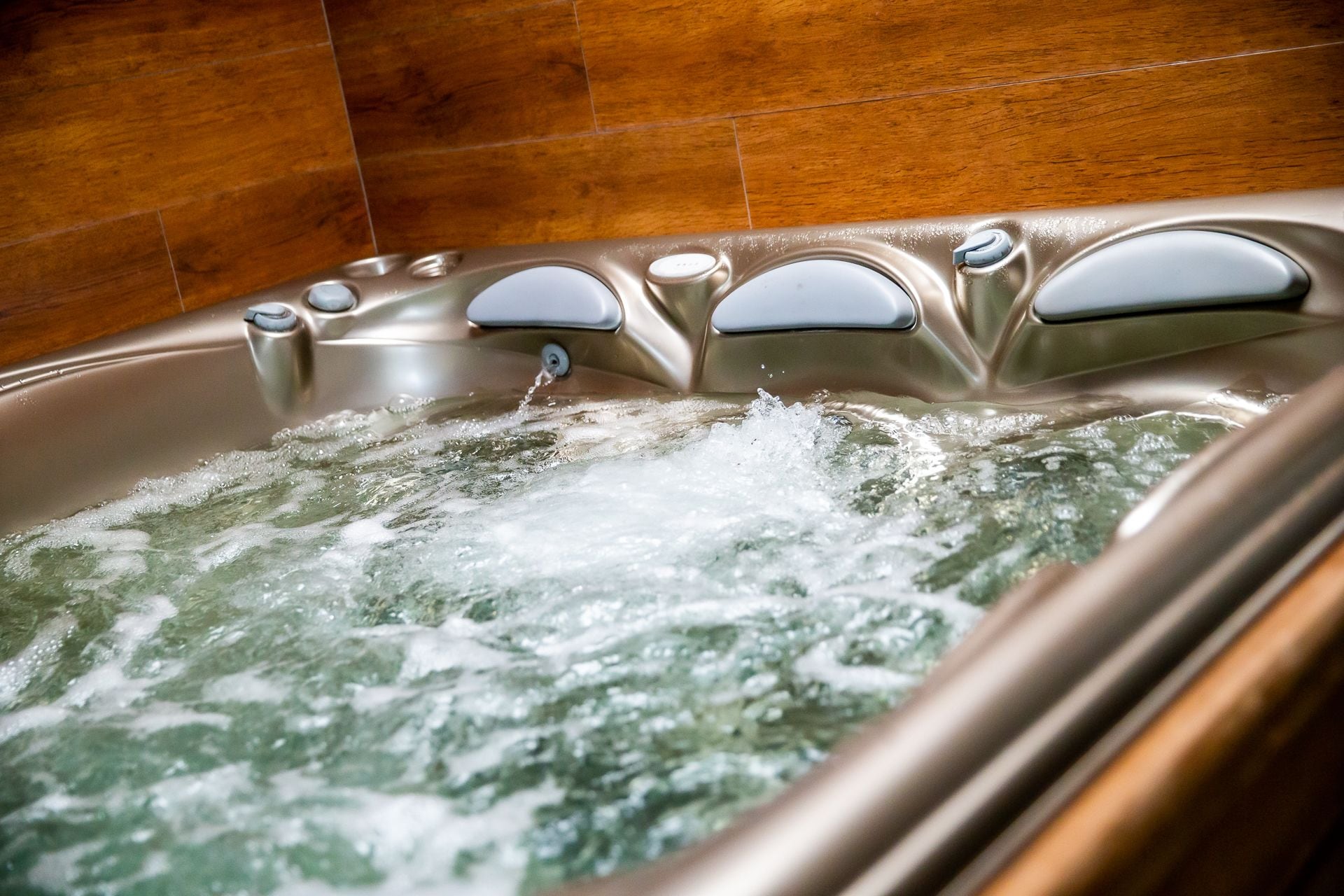 A hot tub with multiple jets, set against a wooden wall.