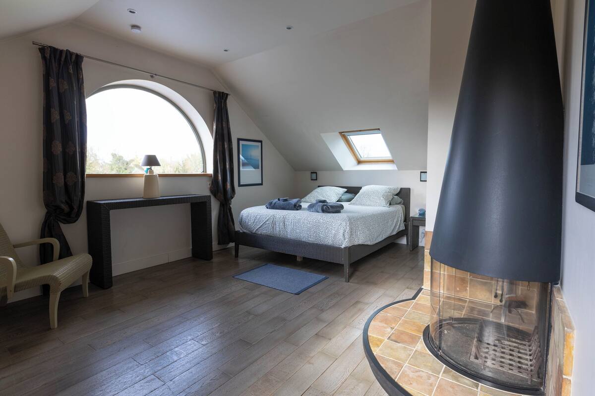 Ein Schlafzimmer mit Bett, Schreibtisch, Stuhl, Kamin und einem Oberlicht.