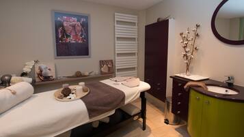 Relax in this serene spa room with a massage table, mirror, and sink.