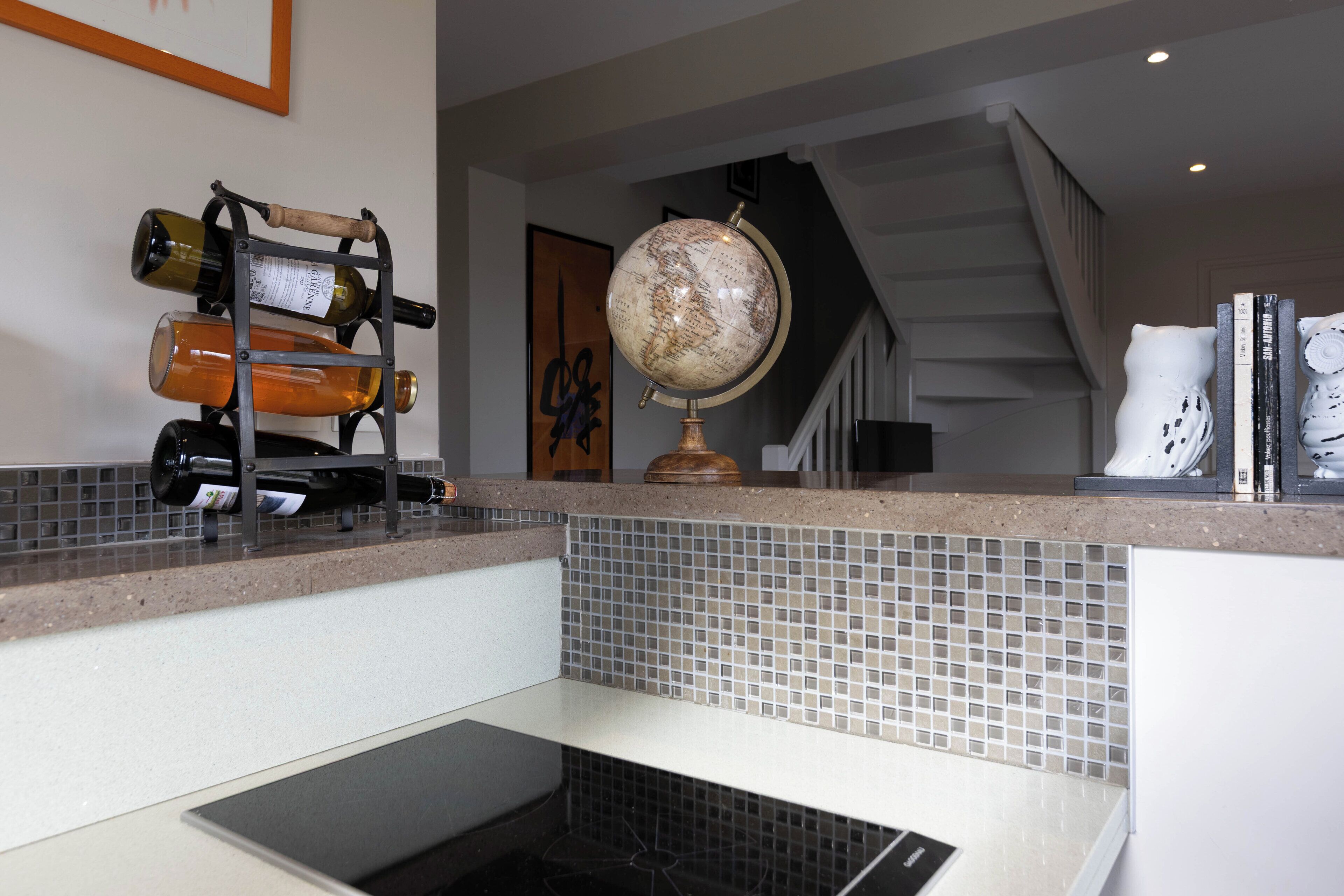 A kitchen with a wine rack, a globe, and a staircase in the background.