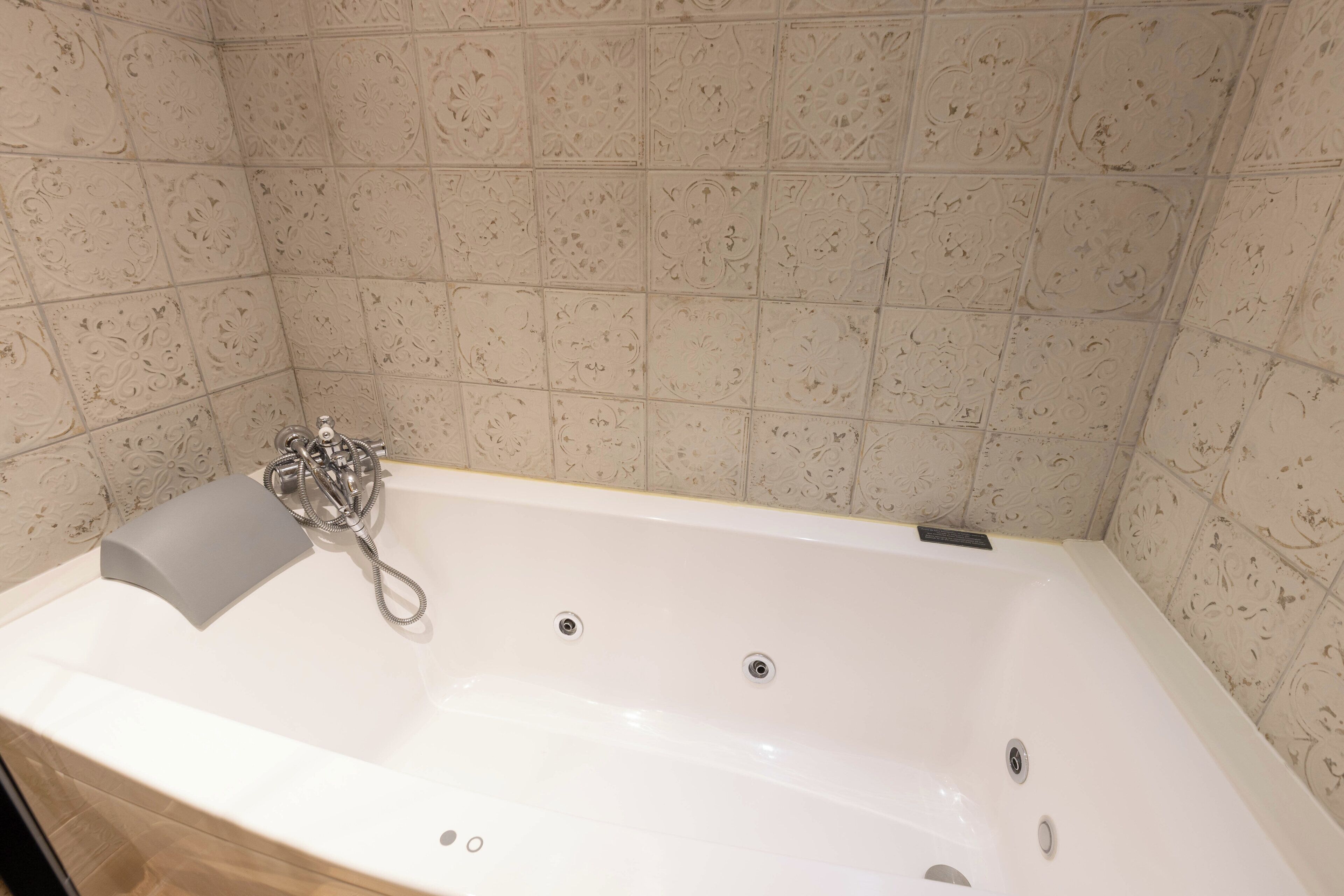 Un baño moderno con una bañera independiente, un cabezal de ducha de mano y un perchero para toallas.