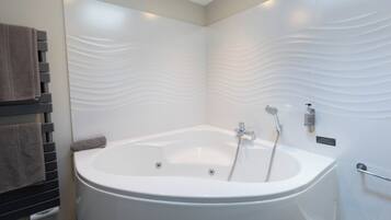 Un baño moderno con una bañera independiente, un perchero para toallas y un dispensador de jabón de pared.
