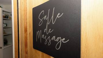 A black sign with white cursive text that reads "Salle de Massage" on a wooden door.