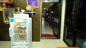 Un hall de hotel con un refrigerador lleno de bebidas, una estatua de Buda y un cuadro enmarcado de un monje.