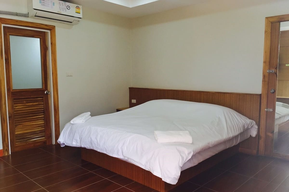 A hotel room with a large bed, wooden headboard, and a tiled floor.