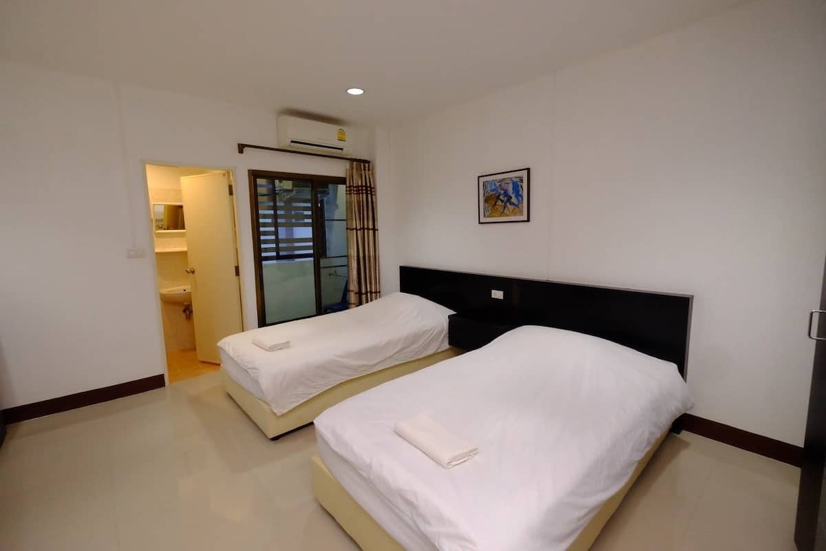 A hotel room with two beds, a bathroom, and a sliding glass door leading to a balcony.