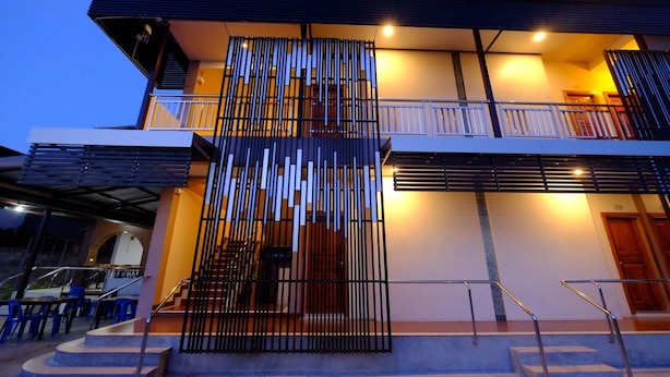Un edificio moderno de dos pisos con un balcón, una escalera y una zona de estar exterior techada.