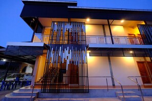A modern two-story building with a balcony, a staircase, and a covered outdoor seating area. - Metha Palace (Sakon Nakhon)