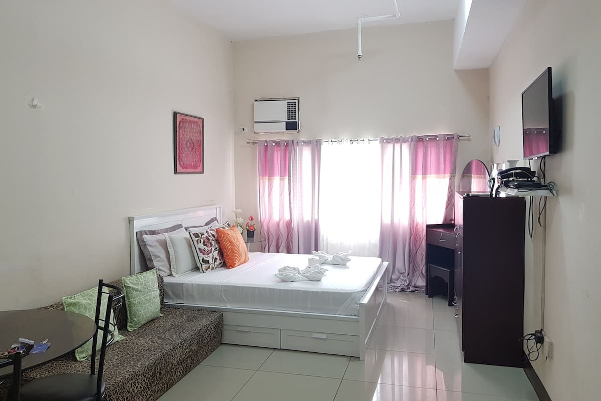 A hotel room with a bed, a sofa, a desk, and a TV.
