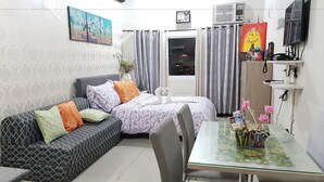 Ein modernes Wohnzimmer mit einer Couch, einem Esstisch und einem Fernseher.