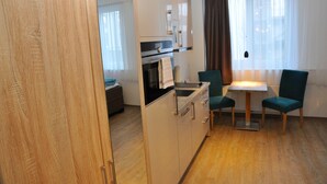 Una cocina compacta con electrodomésticos modernos, una zona de comedor con dos sillas y vistas a la ciudad a través de amplias ventanas.