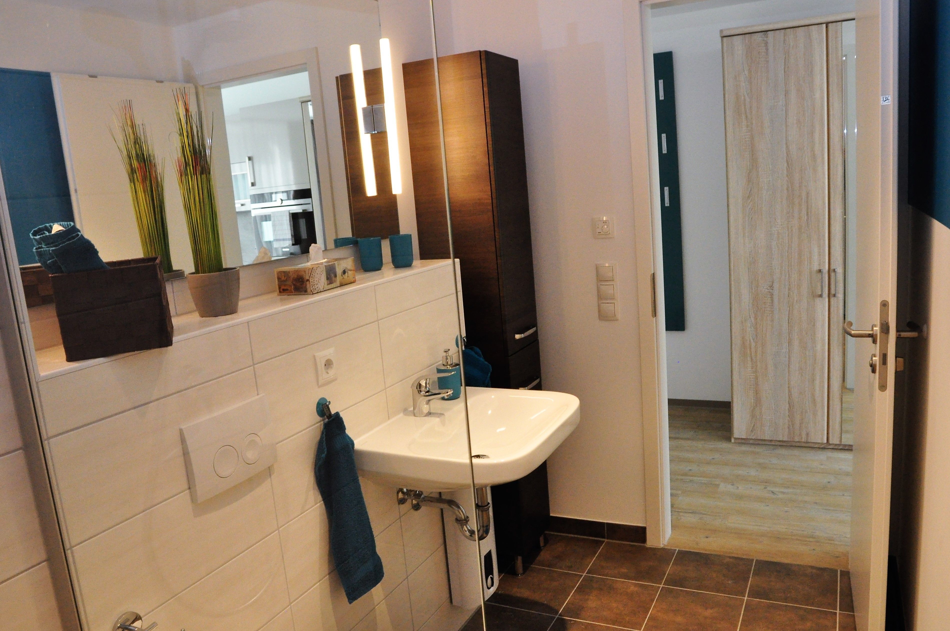 A modern bathroom with a white sink, a mirror, and a wooden cabinet.